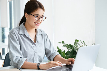 Cheerful business lady working on laptop in office, Asian happy beautiful businesswoman in formal...