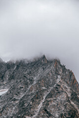 Pico montaña Alpes Suizos con gran nevero de glaciar, cortando con el cielo nublado