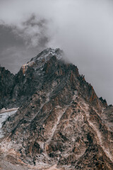 Pico montaña Alpes Suizos con gran nevero de glaciar, cortando con el cielo nublado