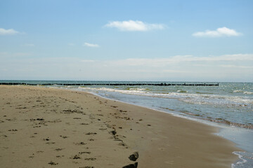 Obraz premium Wooden wave-breaking poles on a sunny day, a row of grooves on the Baltic Sea coast in summer, Helps to reduce the force of waves and coastal erosion. Latvia