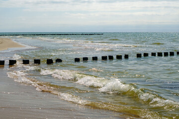 Wooden breakwater poles on a sunny day, on the coast of the Baltic Sea, Latvia. Helps reduce wave power and coastal erosion. Latvia