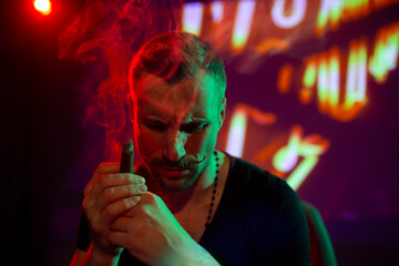 Thoughtful man smoking cigar in modern nightclub interior