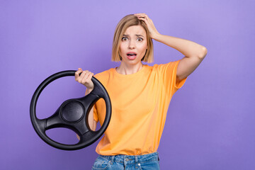Photo of confused horrified girl with bob hairstyle dressed yellow t-shirt hold steering wheel palm on head isolated on violet background