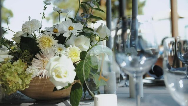 Beautiful wedding table decor, all decorated in pastel white colors. Festive served with bouquet with fresh flowers, plates, glasses on the table, camera moving slow motion.