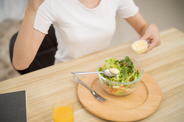 Happy beautiful Asian woman eating healthy food with vegan.salad in the kitchen at home.