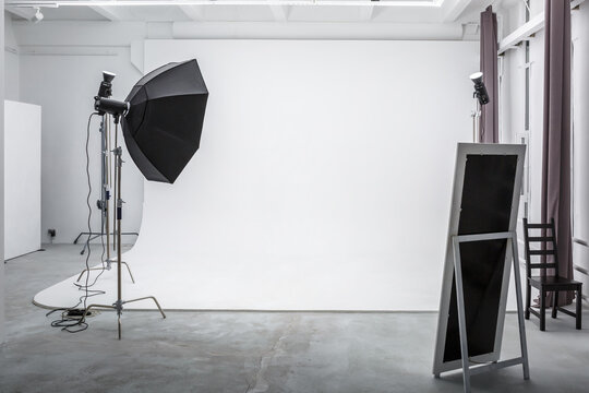 interior of bright space of photo studio with large white cyclorama with lighting equipment