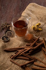 A vertical shot of a cup of tea near cinnamon sticks