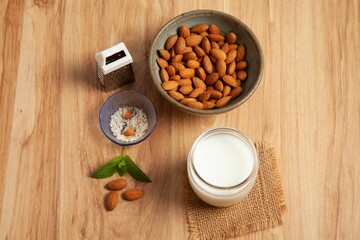 A close-up shot of almonds, fresh mint leaves, and a glass of milk