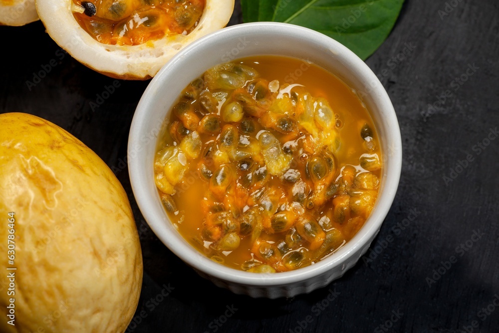 Sticker white ceramic bowl filled to the brim with passion fruit on a black surface