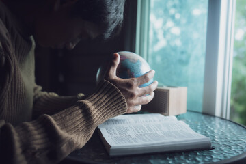Man praying for globe and people around the world with bible in every morning. - obrazy, fototapety, plakaty