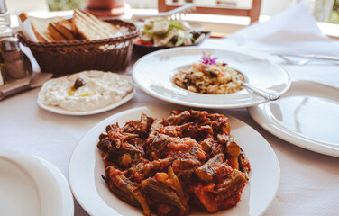 traditional balkan food, baked okra and vegetables with tzatziki on white plates