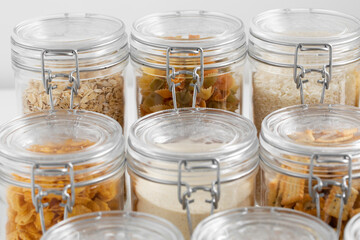 food, culinary and storage concept - close up of jars with different cereals, pasta, beans and cookies on white background