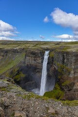 Fototapeta premium Scenic landscape featuring the Haifoss waterfall cascading over a rocky hillside