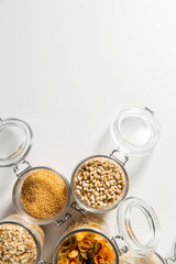 food storage, culinary and eating concept - close up of jars with different cereals, pasta and beans on white background, top view