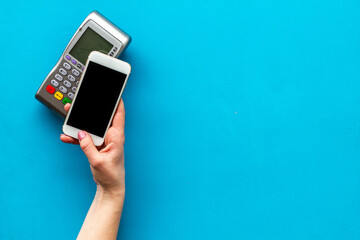 Payment by mobile phone pay. Female hand with mobile phone near POS payment terminal