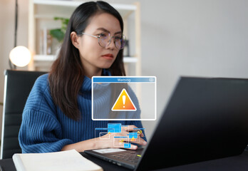 Asian woman using laptop feeling worried of problem message, risk alert symbol while accessing computer device through internet network. Data security protection systems are attacked by cyber threats. - obrazy, fototapety, plakaty