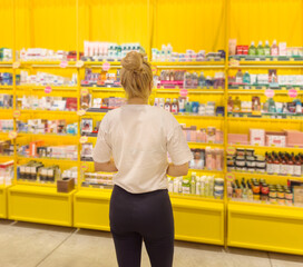 Woman buying make up at cosmetics section in store. choosing cosmetics, perfumes, creams and shampoos, Using tester.