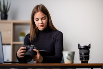 young beautiful woman looking at photos in camera in office