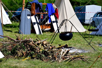 A close up on a medieval camp full of targes, shields, cloth tents, weaponry, and utensils for...