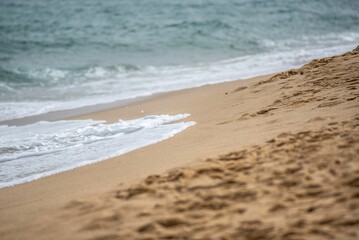 Fototapeta na wymiar Soft ocean waves with foam on a sandy beach