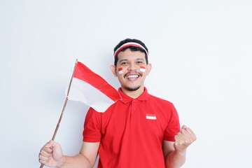 Indonesian man clenched fist, carrying red and white flag, showing excitement when celebrating independence day