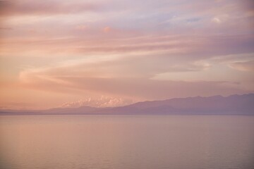 Tranquil lake view with majestic mountains in the distance at sunset © Buellom/Wirestock Creators