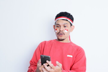 Indonesian man showing wow expression while holding a mobile phone during independence day celebration