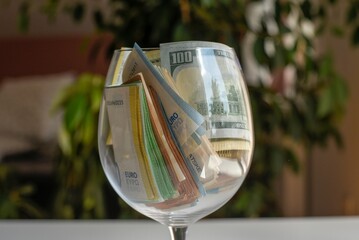 Close up of a cup filled with different money bills © Lucija Kanižaj/Wirestock Creators
