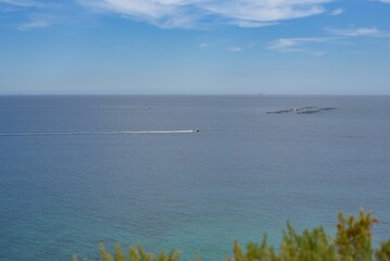 two ships are sailing off the coast in the distance and on the horizon, another