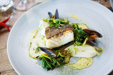 Cod fillet with cauliflower cream, asparagus, clam-wine sauce and mussles. Delicious seafood fish closeup served on a table for lunch in modern cuisine gourmet restaurant - 630806045