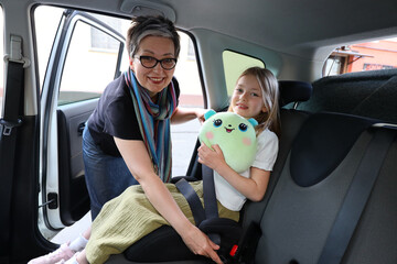 A caring and happy mother and her little daughter sit in the car. They are a beautiful and loving...