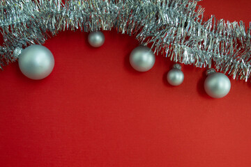 Christmas background with copy space. Christmas balls and silver tinsel on a red background.