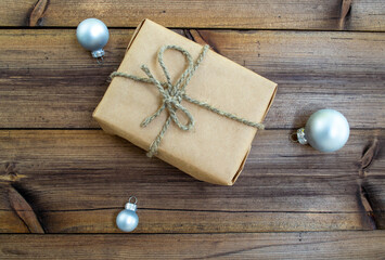 New Year's gift. A gift in craft paper and Christmas balls on a wooden background.