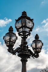 Fototapeta na wymiar Vertical shot of a lamppost in a park under a blue sky and sunlight