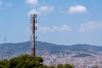 Big tower with antennas and satellites in front of the mountains and the city of Barcelona, no...