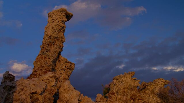 Sun shining on tufa rock formations at Mono Lake in the Eastern Sierra area of California with clouds moving quickly across a blue sky