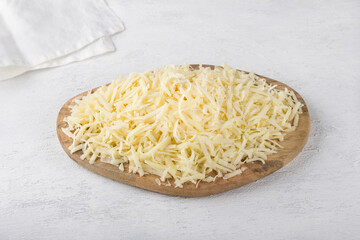 Wooden board with grated hard cheese on a light gray background. Cooking delicious vegetarian food