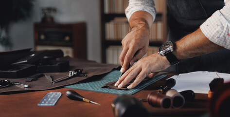 Tailor cobbler hold different rolls natural brown leather, working with textile in workshop....