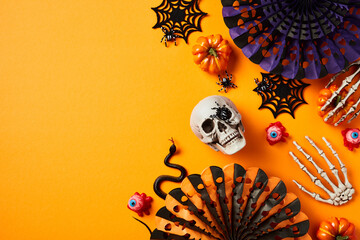 Halloween flat lay composition with skull, spider webs, snake, skeleton hands, paper fans on orange...