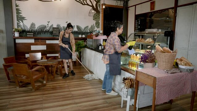 Asian single mother cafe owner family small business And beautiful daughter helping to clean the shop and wipe glass cabinet of sweets. In evening after closing shop to prepare to open shop tomorrow