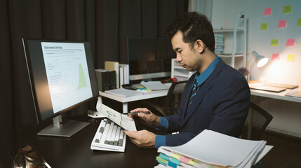 Fototapeta na wymiar Stressed and tired Asian young man feels headache while working overtime at night in his office.