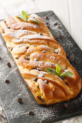 Braided brioche stuffed with chocolate and custard close-up on a slate board on the table. Vertical