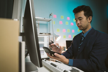 Young Asian businessman talking on the phone
late night hustle ambitious Working overtime talking on the phone in the organization