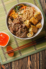 Bowl of traditional Vietnamese noodle salad Bun Bo Nam Bo, with beef, rice noodles, fresh herbs,...