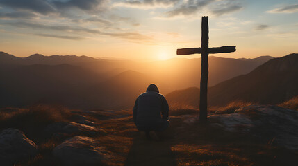 Silhouette of a man kneeling praying at the Cross of Jesus on a hill at sunrise - obrazy, fototapety, plakaty