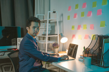 young man working at night Work comfortably on your smartphone. Social media chat at the office