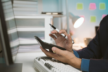 Obraz premium young man working at night Work comfortably on your smartphone. Social media chat at the office