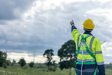 Engineer male working in wind turbines farm back view hand pointing at the sky for future of eco clean energy worker people