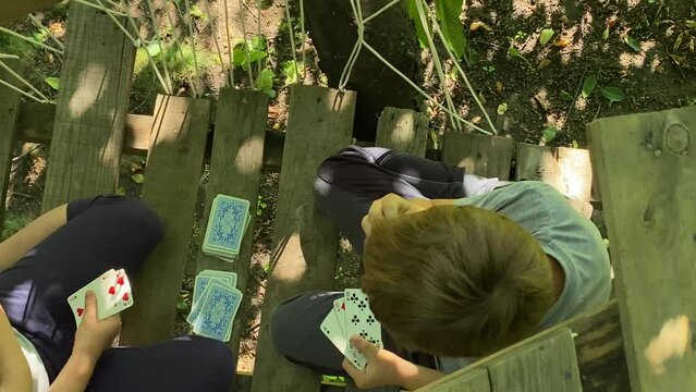 Top view lovely kids find joy and entertainment in secret hideaway. Inside the cozy treehouse children engage in a friendly card game, creating cherished memories of togetherness and childhood bonding