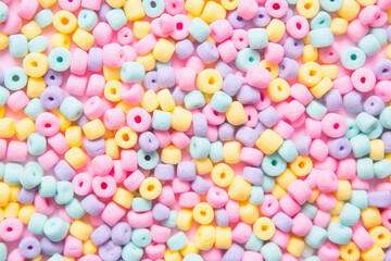 Fototapeta na wymiar Crunchy breakfast cereal texture. Delicious wallpaper with crispy dry breakfast rings in different rainbow pastel colors. Cute sweet food backdrop, top view.